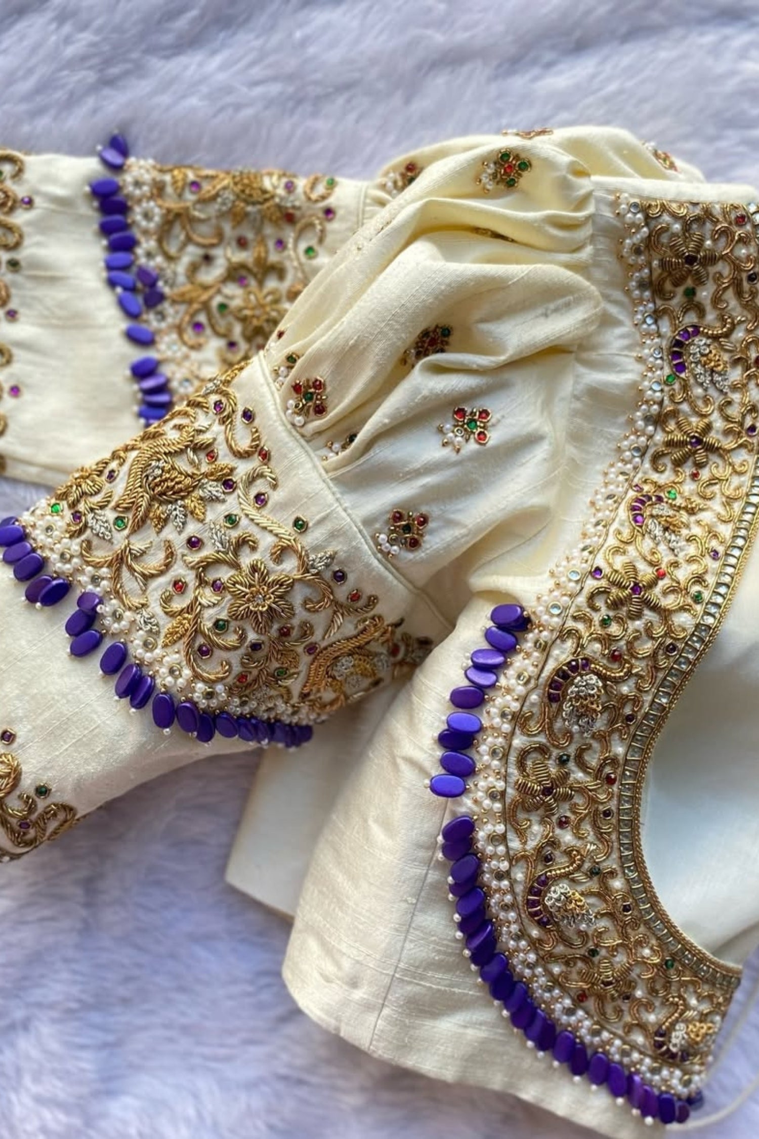 Decorative blouse with intricate gold and purple embroidery on a white background