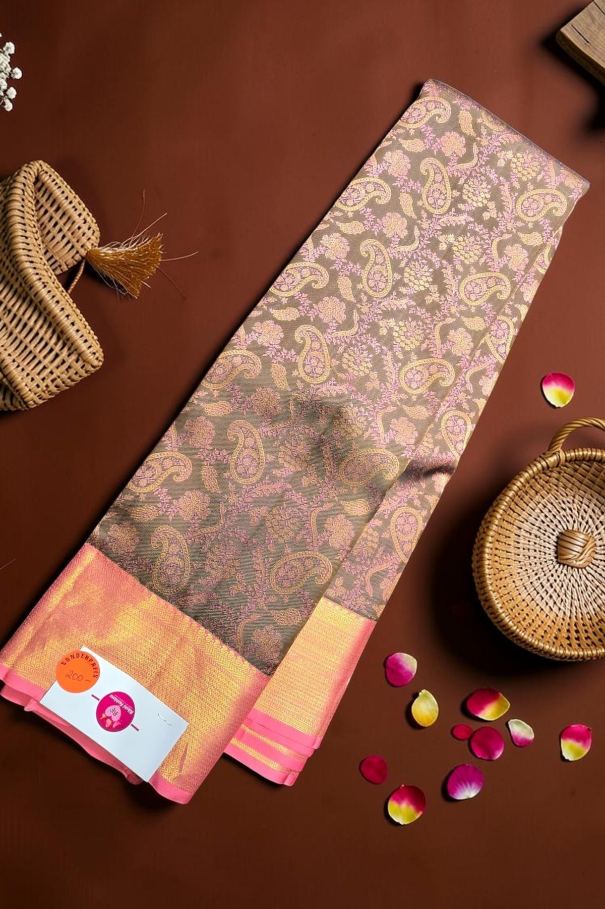 Saree with a paisley pattern on a brown surface with baskets and petals