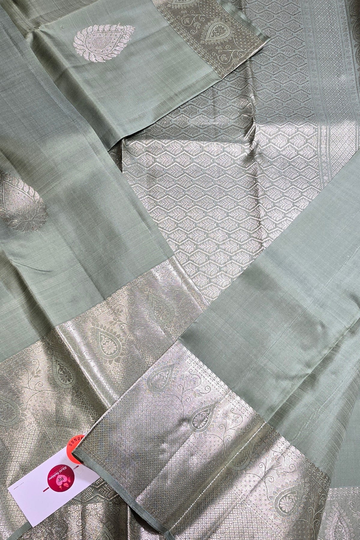 Green fabric with intricate patterns and a visible brand tag.