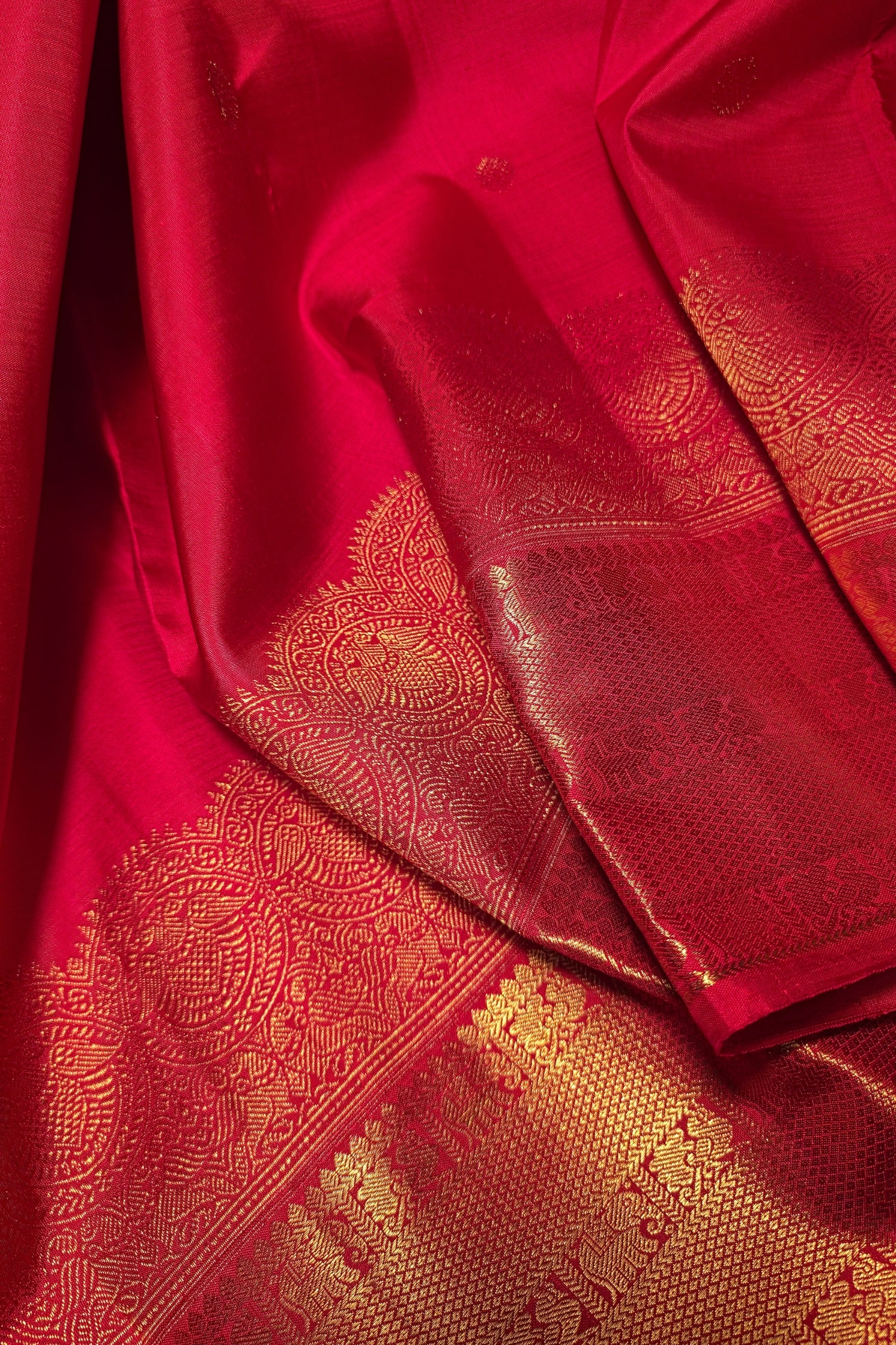 crimson red silk saree with gold embroidery featuring intricate zari designs and a luxurious wide gold border