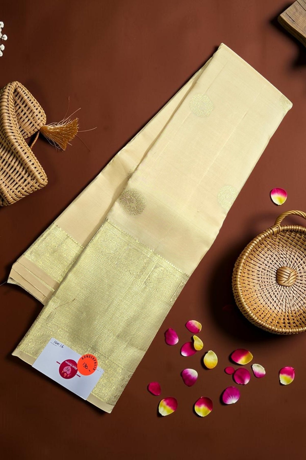 Beige saree with green border on a brown background with decorative elements