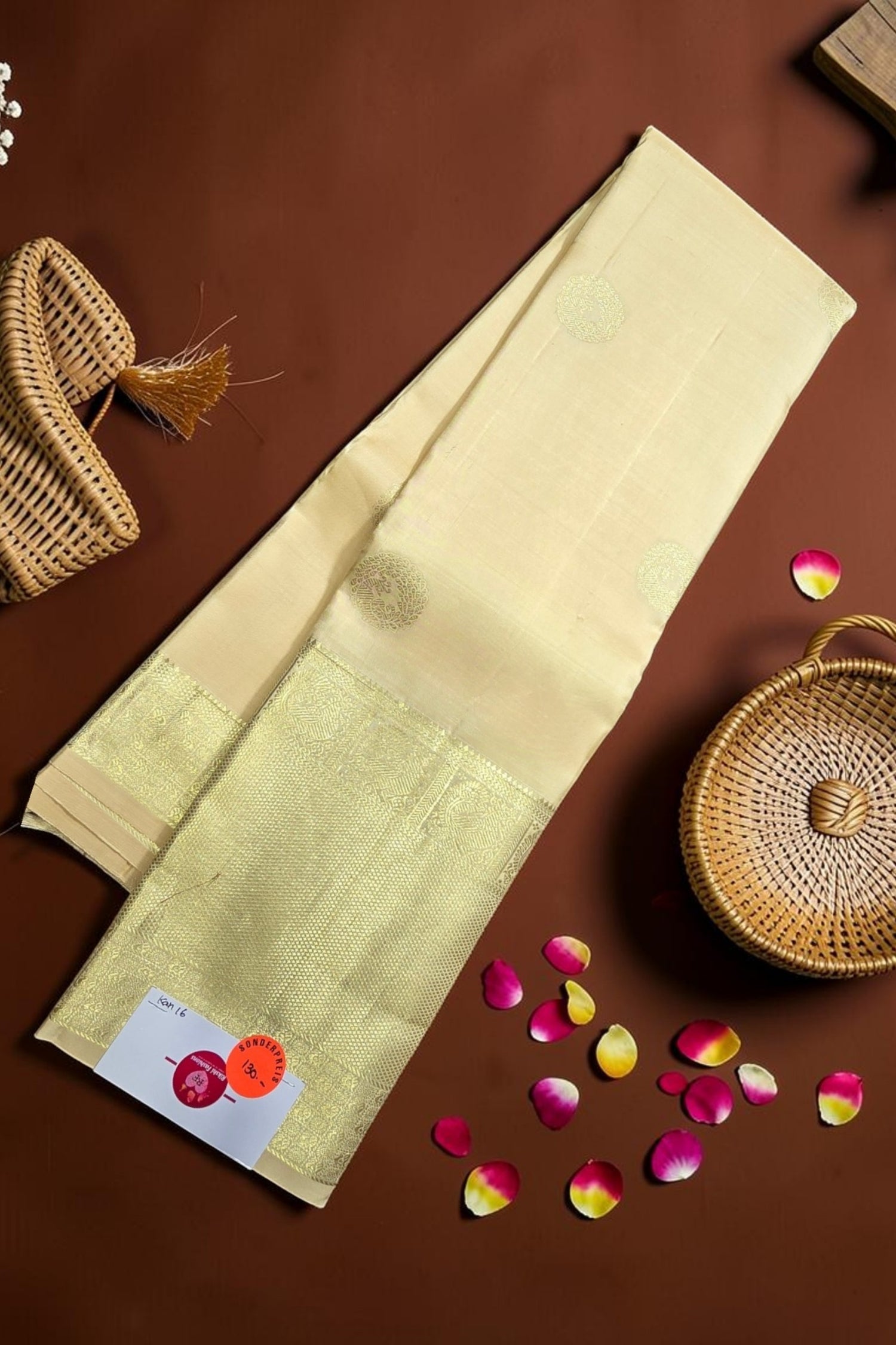 Beige saree with green border on a brown background with decorative elements