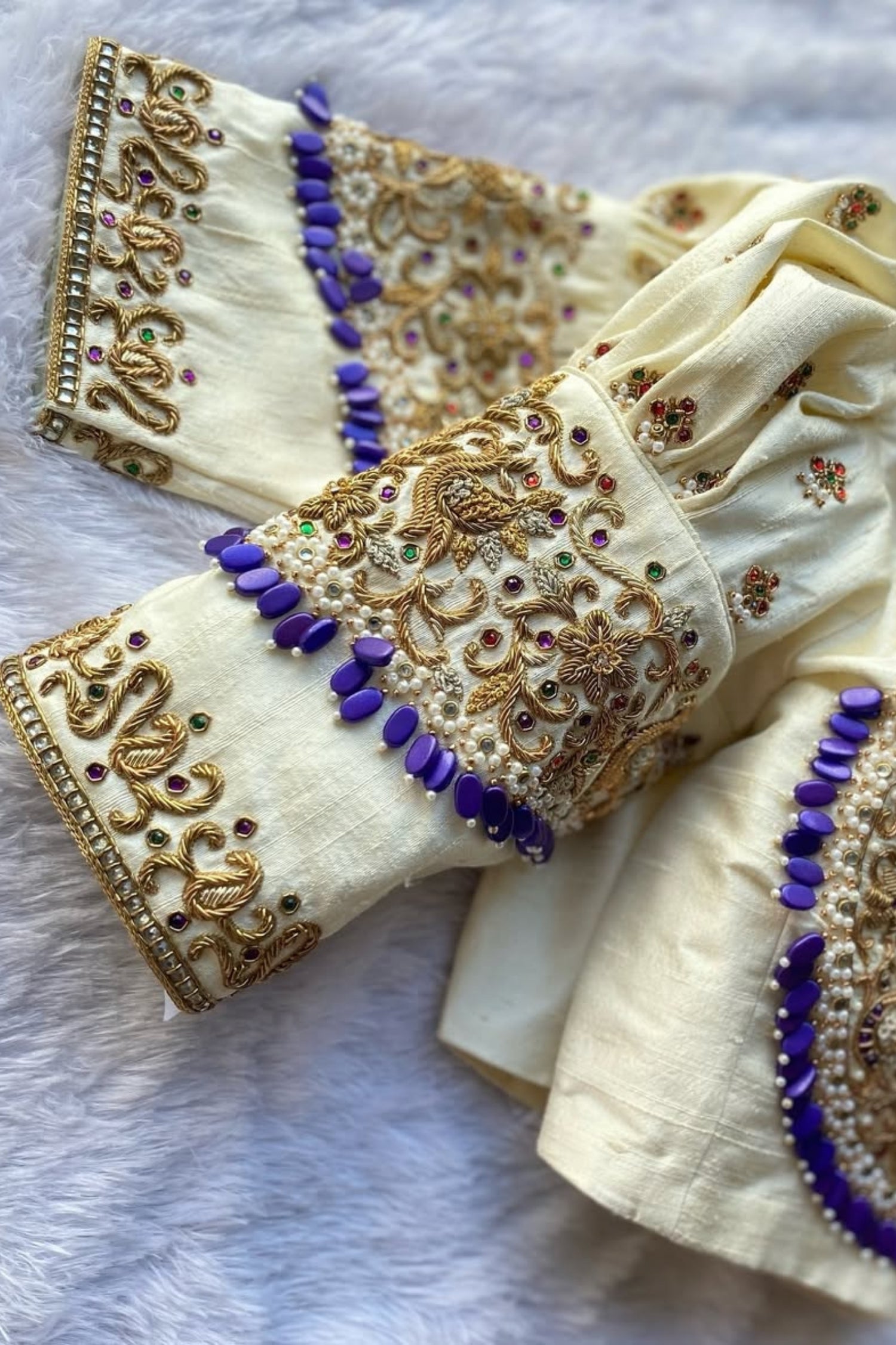 Decorative fabric with gold, purple, and multicolor embroidery on a white background