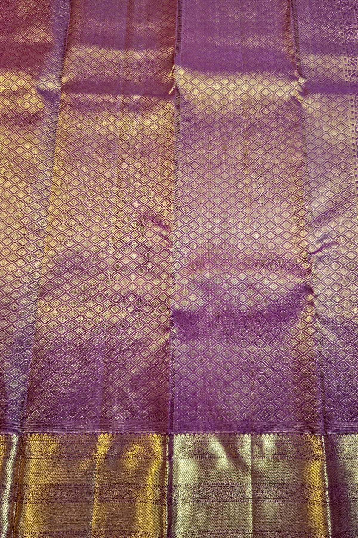 Purple silk saree fabric with intricate gold zari woven patterns and a wide decorative gold border.