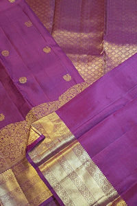 A close-up of a purple silk saree with intricate gold zari woven patterns and borders.