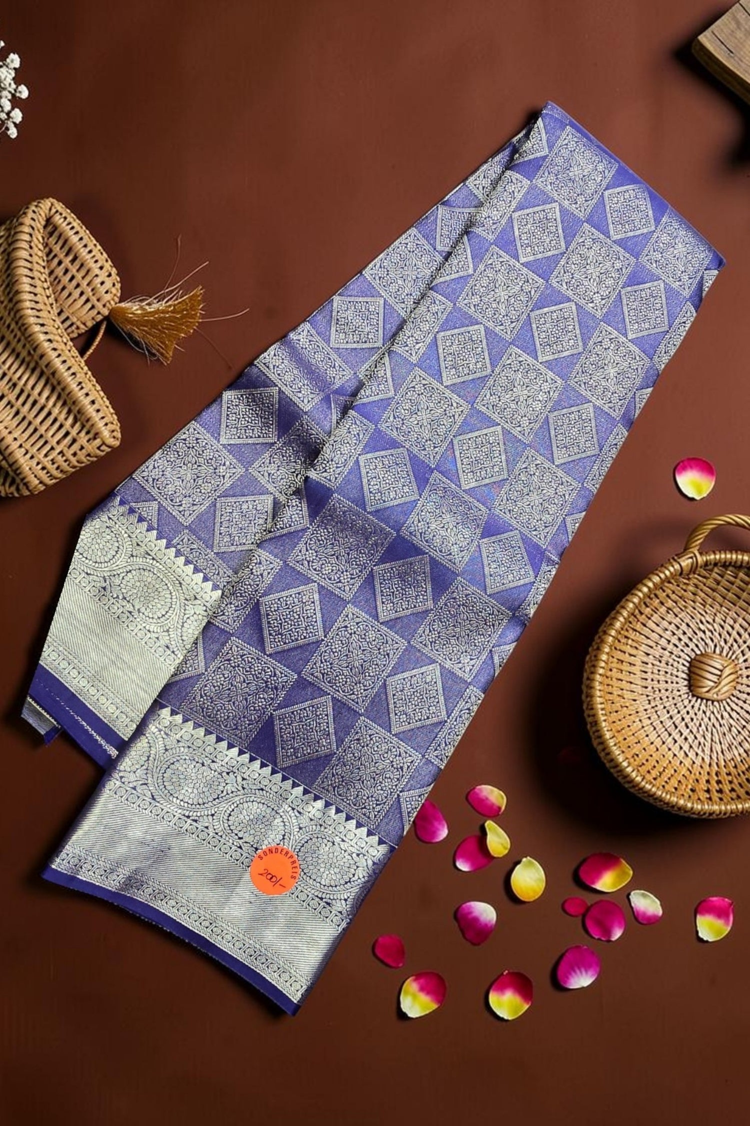 Blue and white patterned fabric on a brown surface with wicker baskets and rose petals.