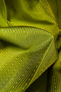 Close-up of green saree with gold zari border, showcasing intricate gold detailing on lush green fabric.