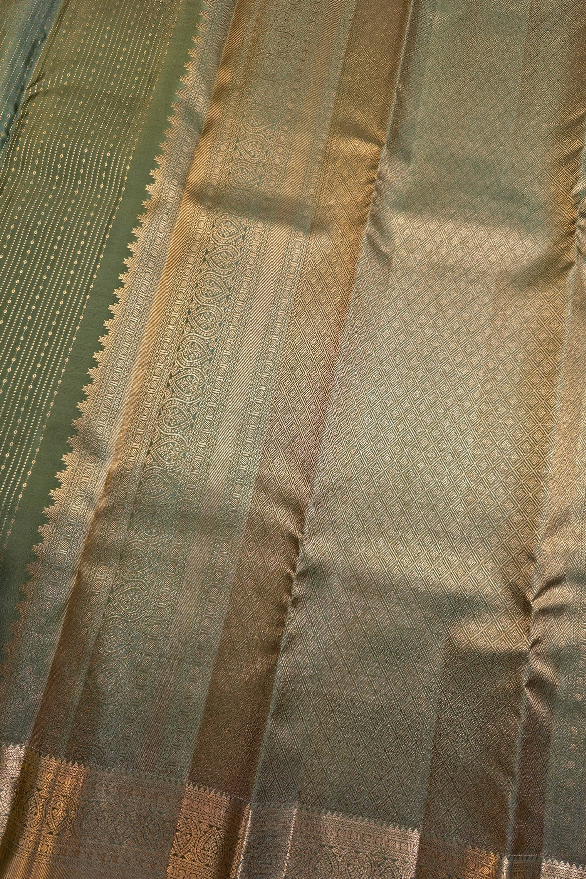 Close-up of a woven fabric with vertical stripes in olive green, beige, and metallic gold, showing detailed brocade patterns and a scalloped border.