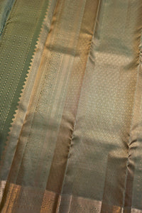Close-up of a woven fabric with vertical stripes in olive green, beige, and metallic gold, showing detailed brocade patterns and a scalloped border.