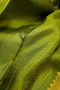 Close-up of a green saree with gold zari border showcasing intricate patterns and luxurious fabric texture.