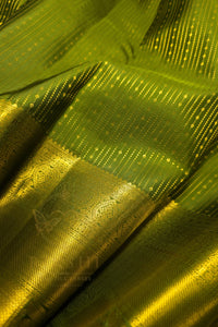 Green saree with gold zari border close-up, showcasing intricate patterns and luxurious texture.