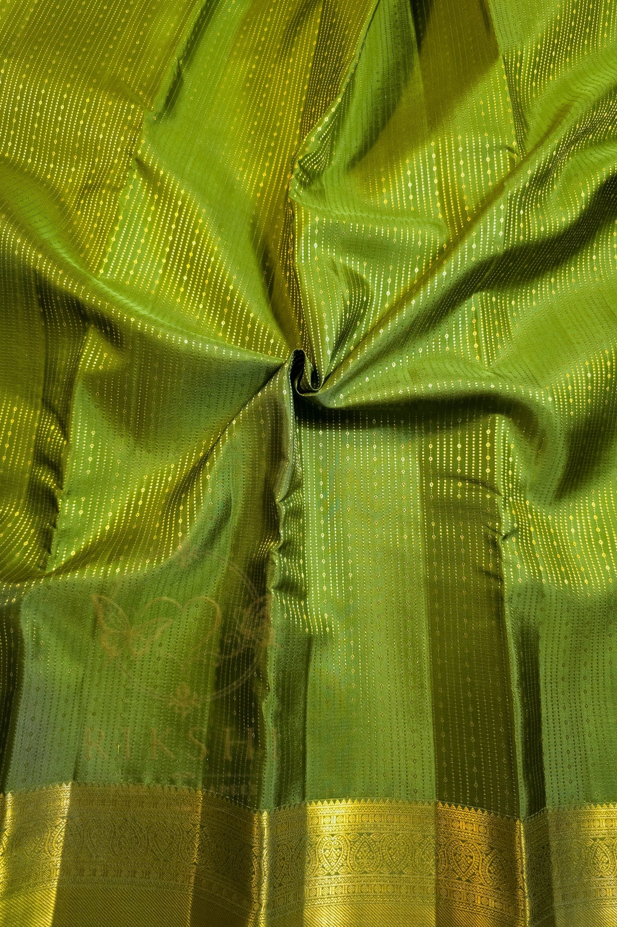 Green saree with gold zari border showcasing intricate detailing and rich texture.