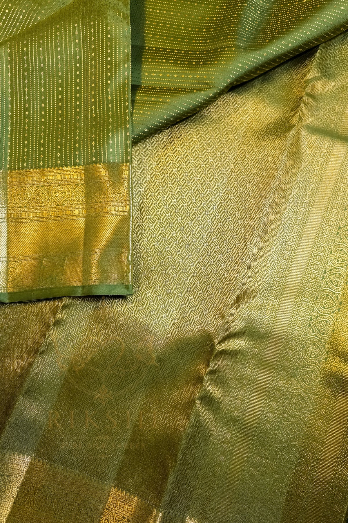 Green saree with gold zari border showcasing intricate patterns and luxurious texture.