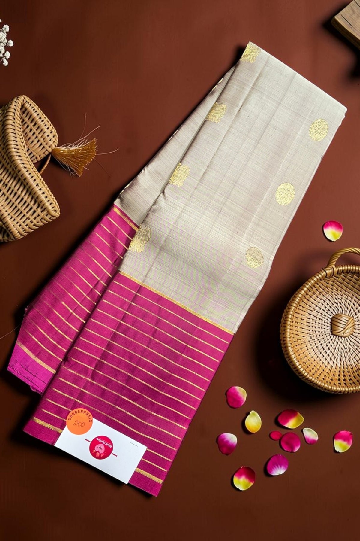 Saree with pink and white pattern on a brown surface with decorative elements.