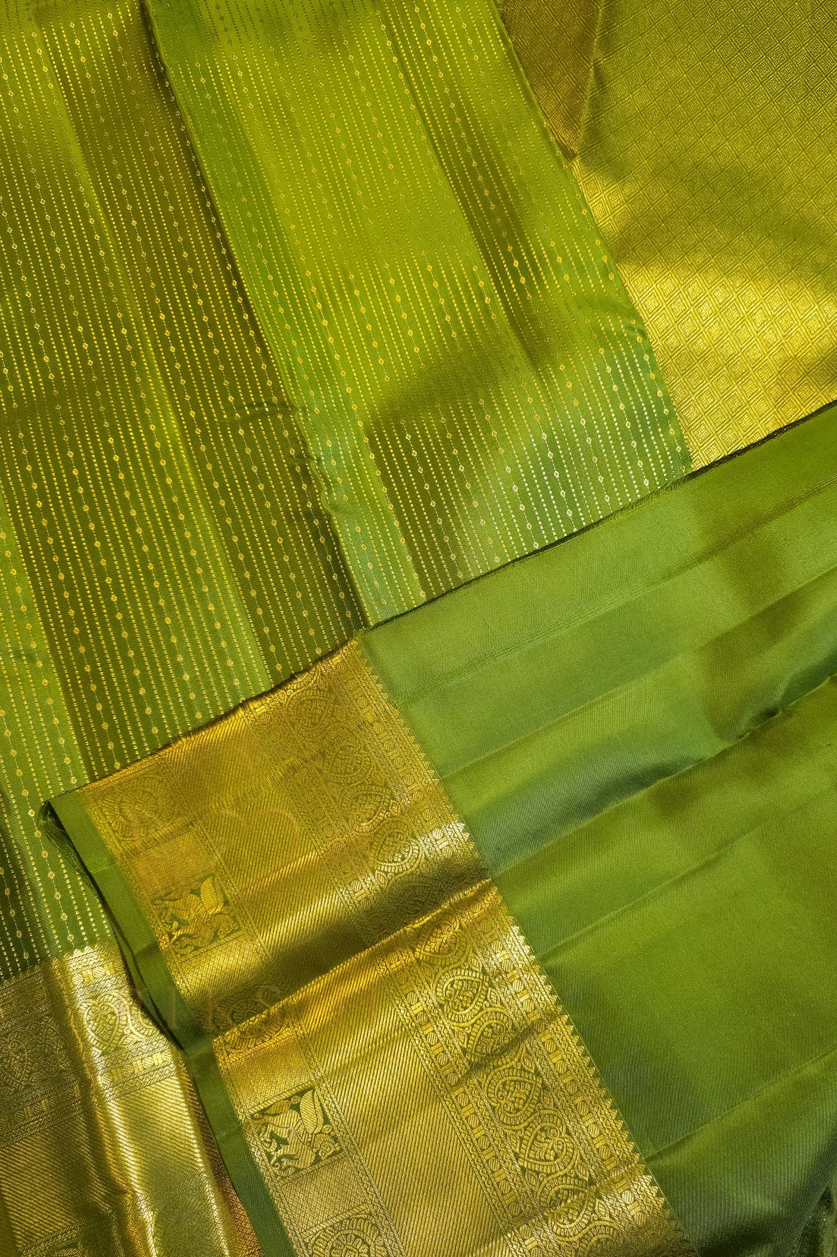 Green saree with gold zari border showcasing rich textures and luxurious fabric.