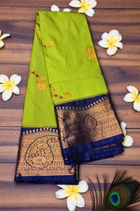 Green saree with gold and blue border on a wooden surface with flowers