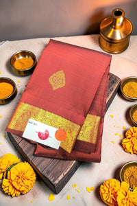 Red saree with gold border on a wooden board, surrounded by yellow flowers and small bowls.