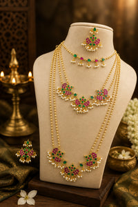 Gold necklace with pink and green gemstones on a mannequin bust with a warm background.
