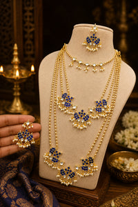 Gold and blue jewelry set on a mannequin bust with a decorative background.