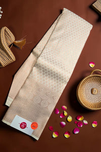 Beige towel with a pattern on a brown surface with wicker baskets and flower petals.