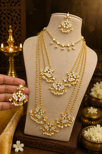 Gold necklace and earrings set on a mannequin bust with decorative background