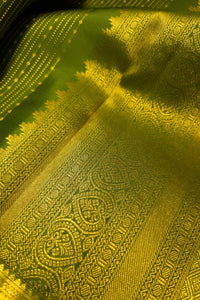Close-up of green saree with gold zari border showcasing intricate patterns and luxurious texture.