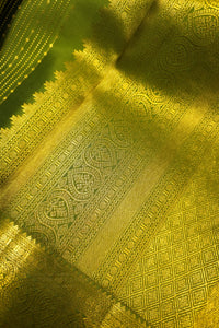 Close-up of green saree with gold zari border showcasing intricate gold zari designs and patterns.