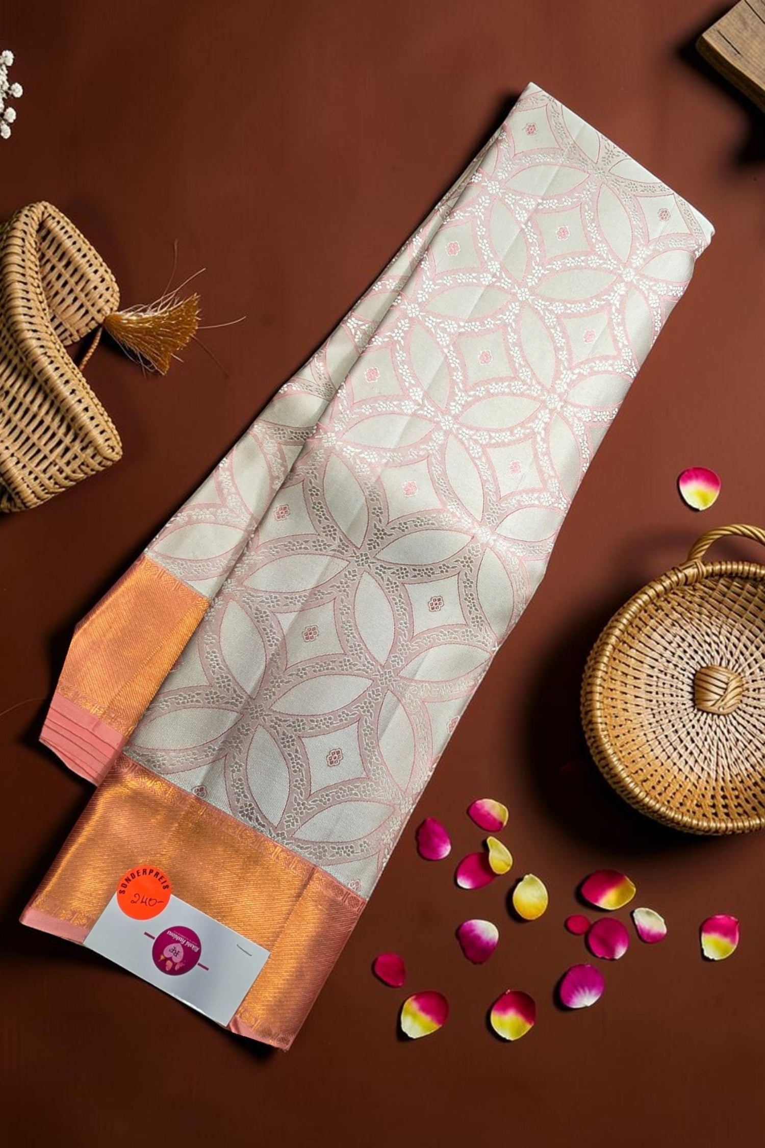 Patterned fabric with orange accents on a brown surface with wicker baskets and flower petals.