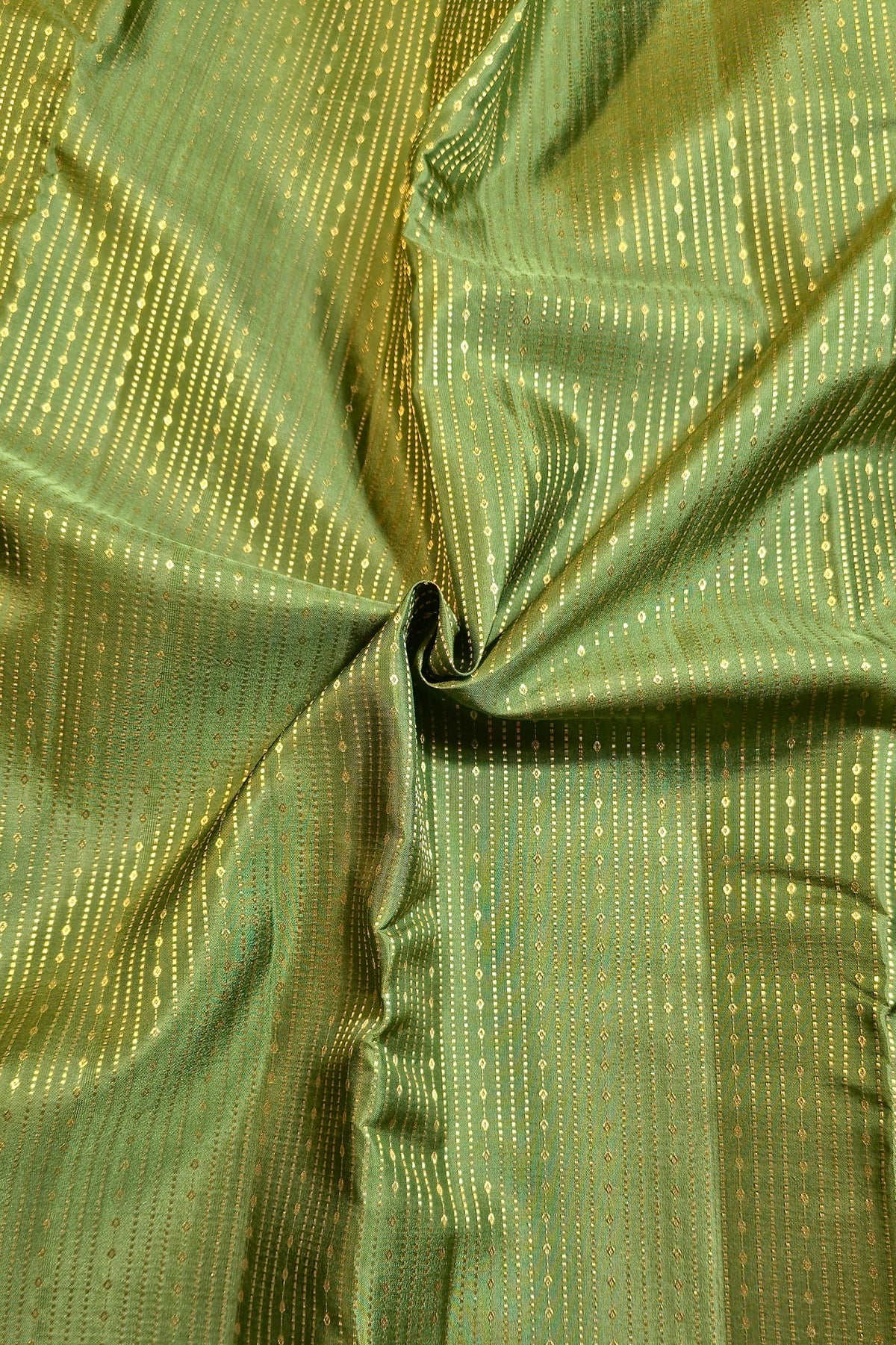 A close-up of olive green fabric with a subtle sheen and vertical dotted metallic-looking stripes, gathered in the center to show texture and drape.
