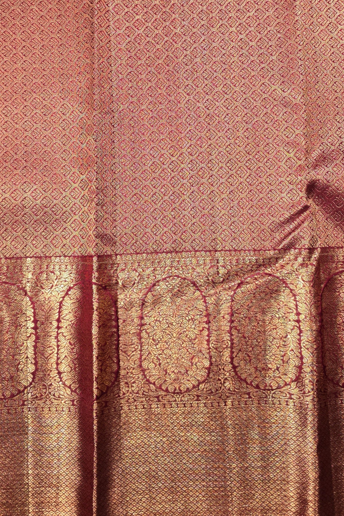 Close-up of a pink and gold patterned fabric with intricate designs.