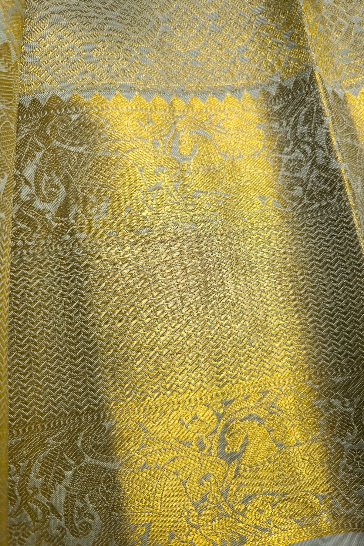 Light sage green silk saree with intricate gold zari border showcasing fine craftsmanship and elegant design.