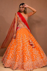 Woman wearing an orange and red traditional outfit against a brown background