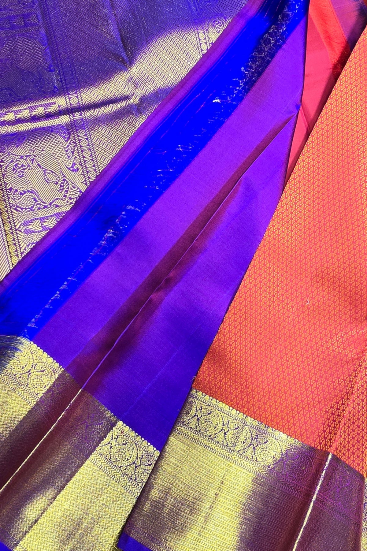 Close-up of a traditional fabric with purple, red, and gold patterns.