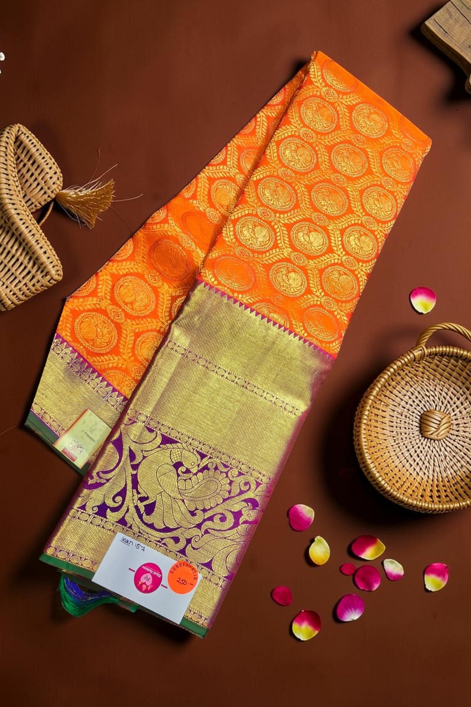 Orange and green saree with intricate patterns on a brown background