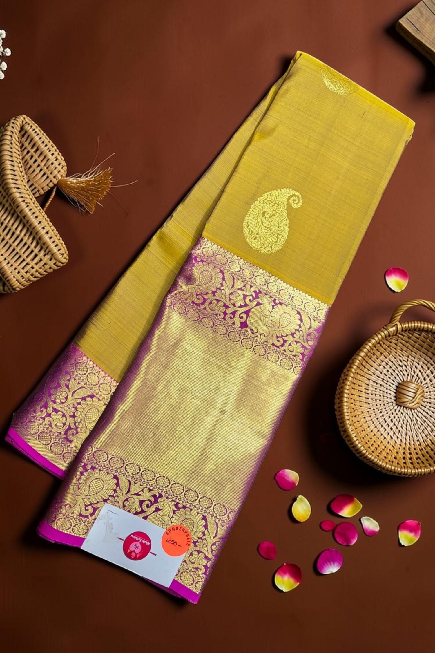 Yellow saree with pink border on a brown background