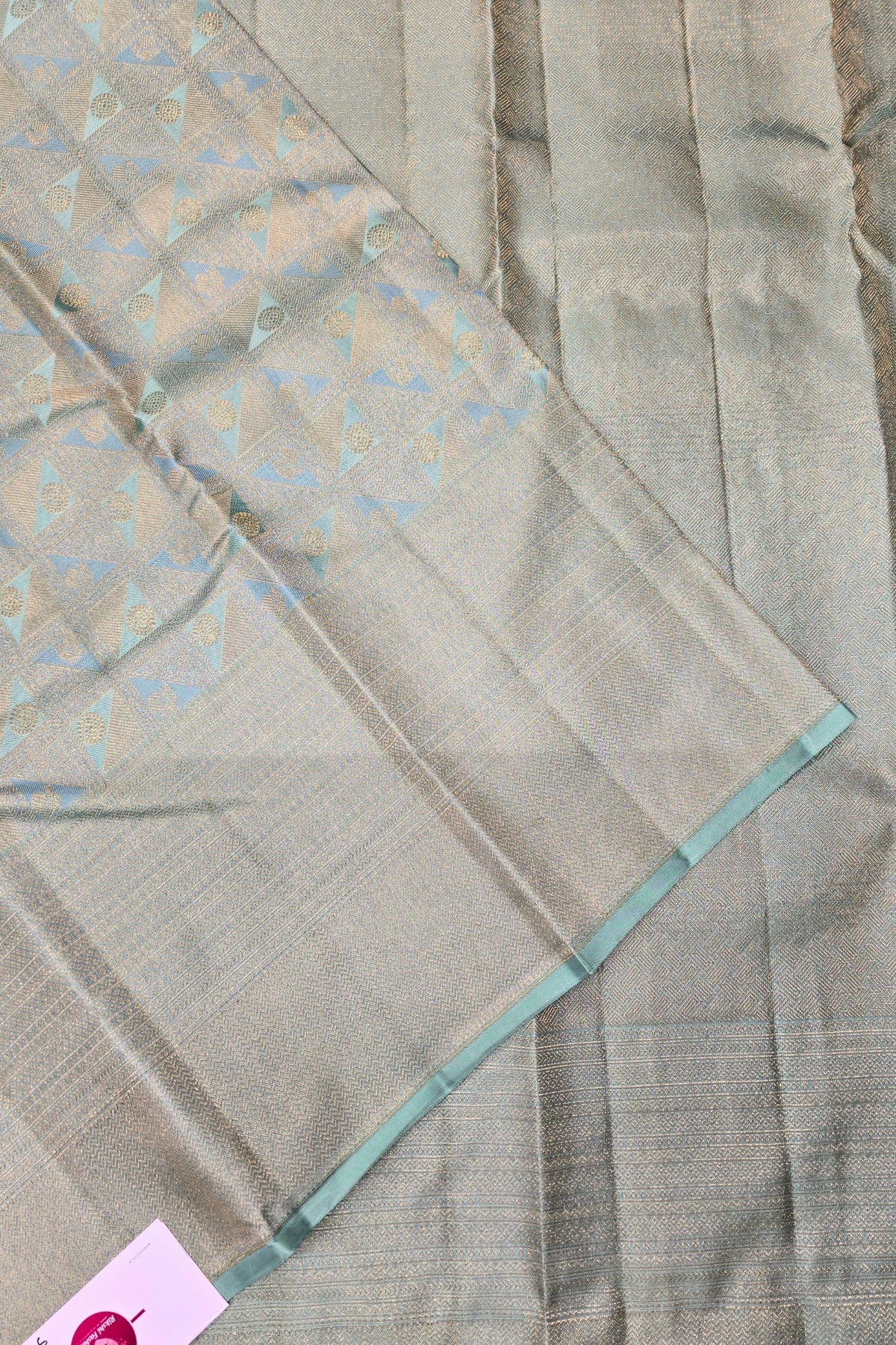 Gray fabric with a subtle pattern and green border, possibly a sari or fabric swatch.