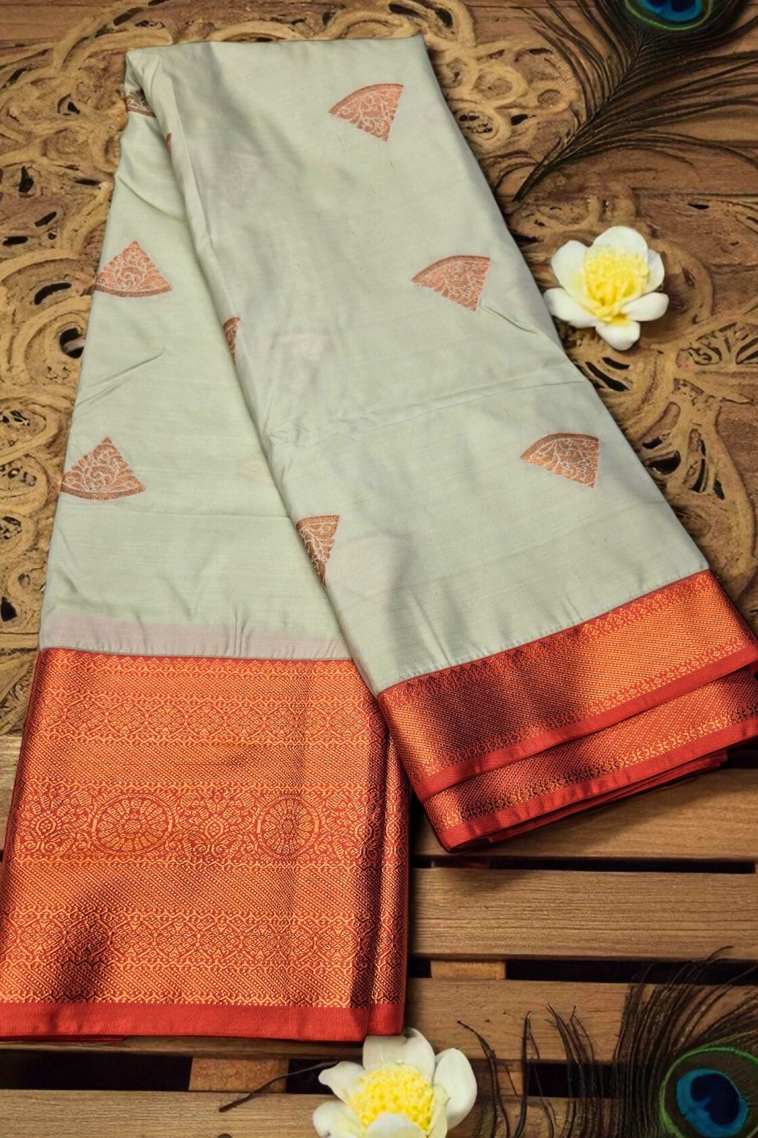 Light green saree with orange border on a wooden surface