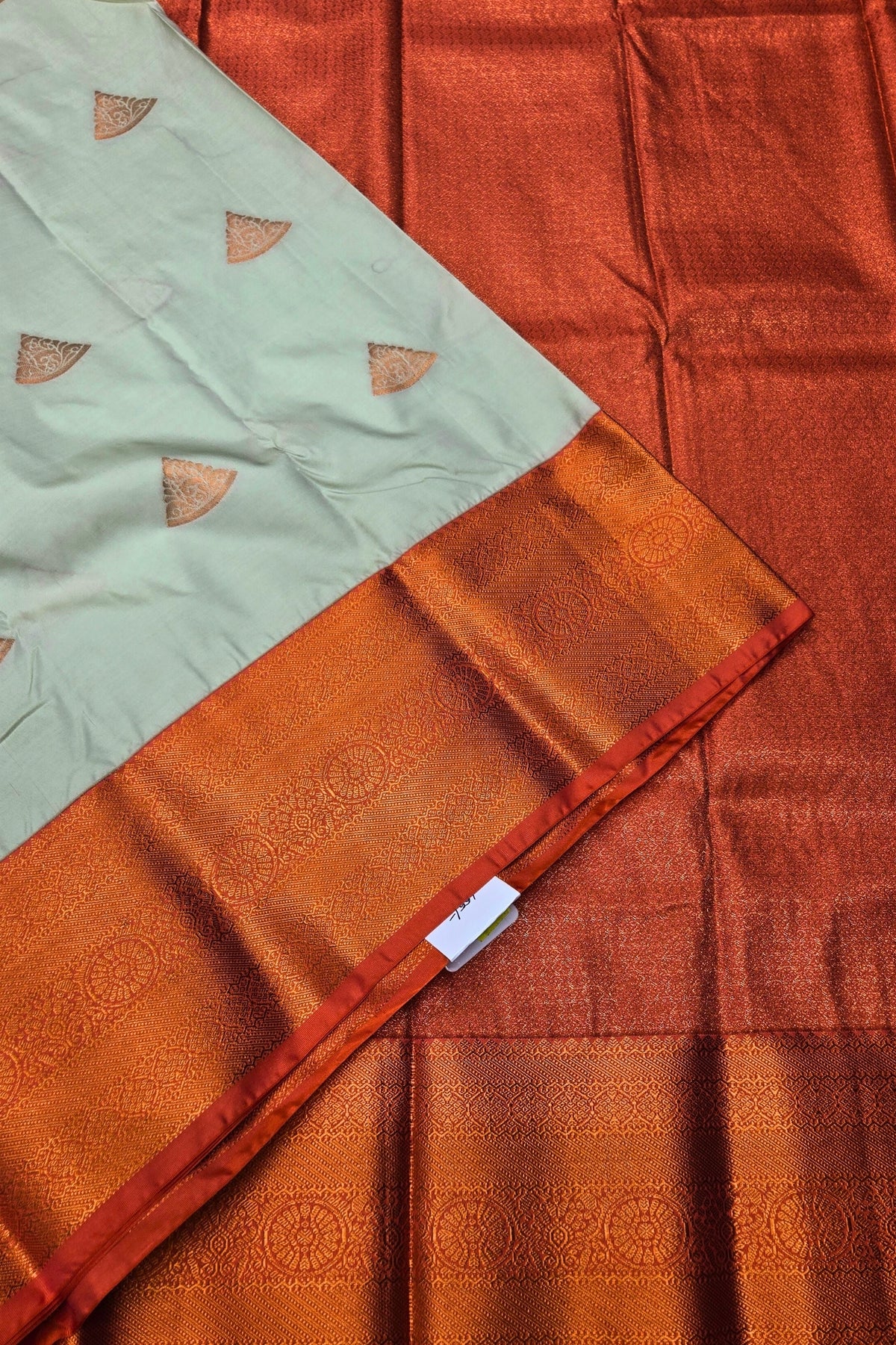 Close-up of a traditional saree with a light green border and orange fabric.