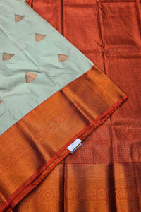 Close-up of a traditional saree with a light green border and orange fabric.