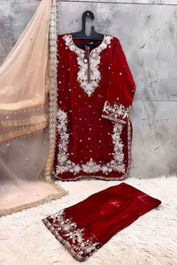 Red embroidered traditional outfit with matching dupatta on a textured surface