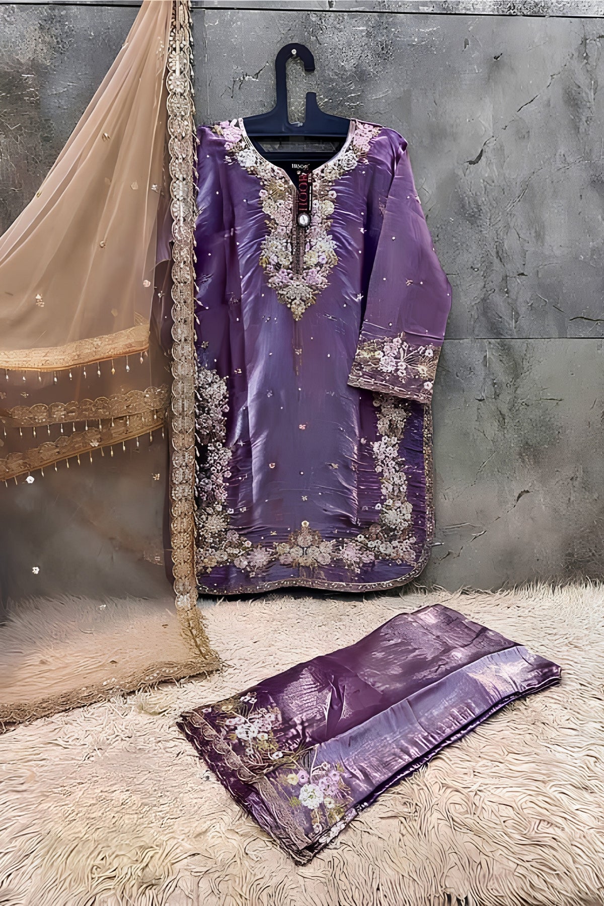 Purple embroidered traditional outfit with a matching dupatta on a textured surface.