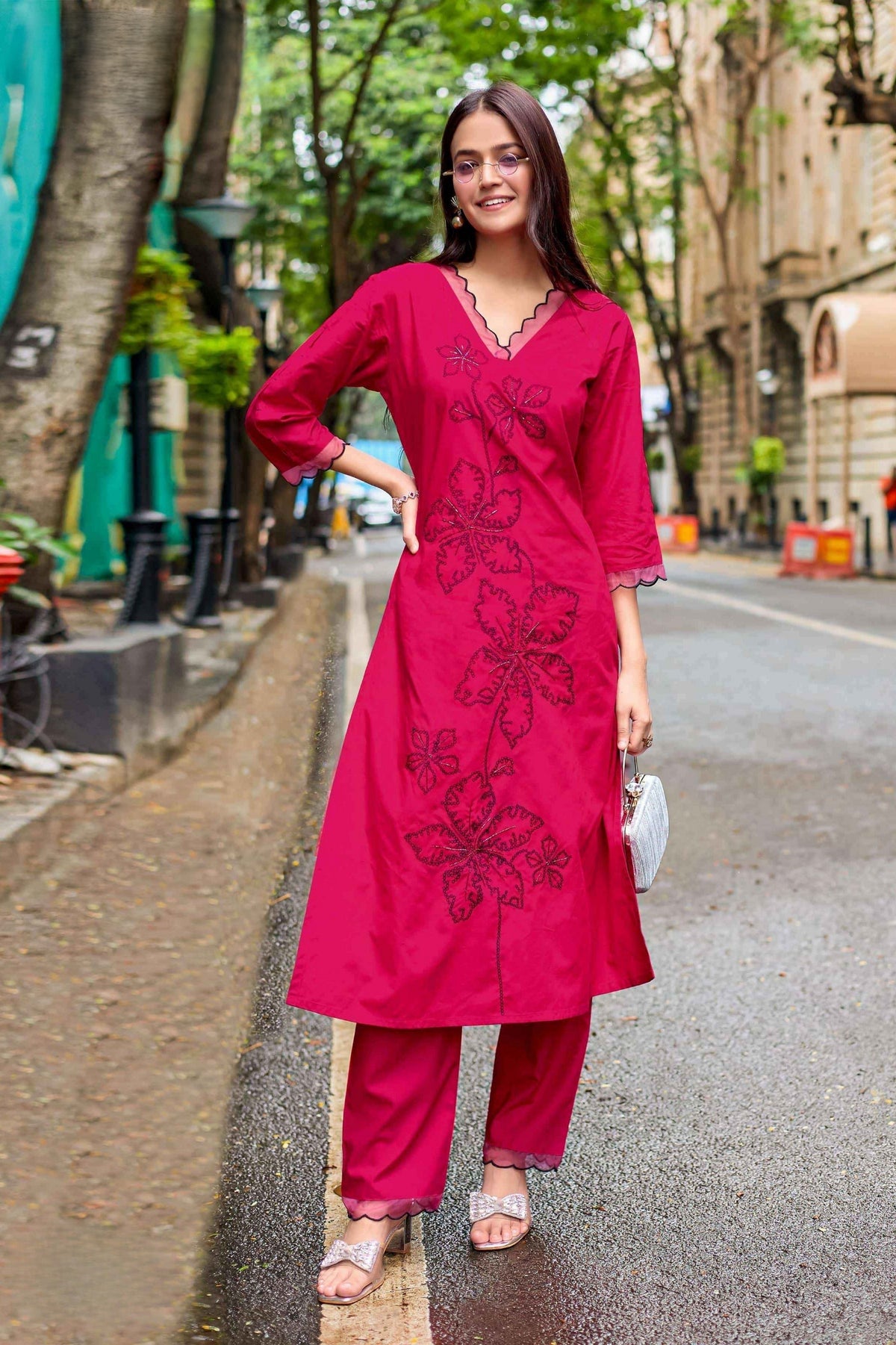 Woman in a red traditional outfit standing on a street.