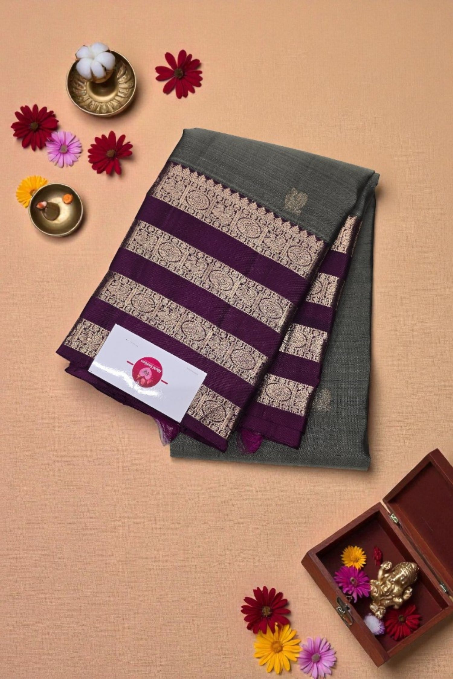 Decorative scarf with purple and gold stripes on a beige background with flowers and a box.