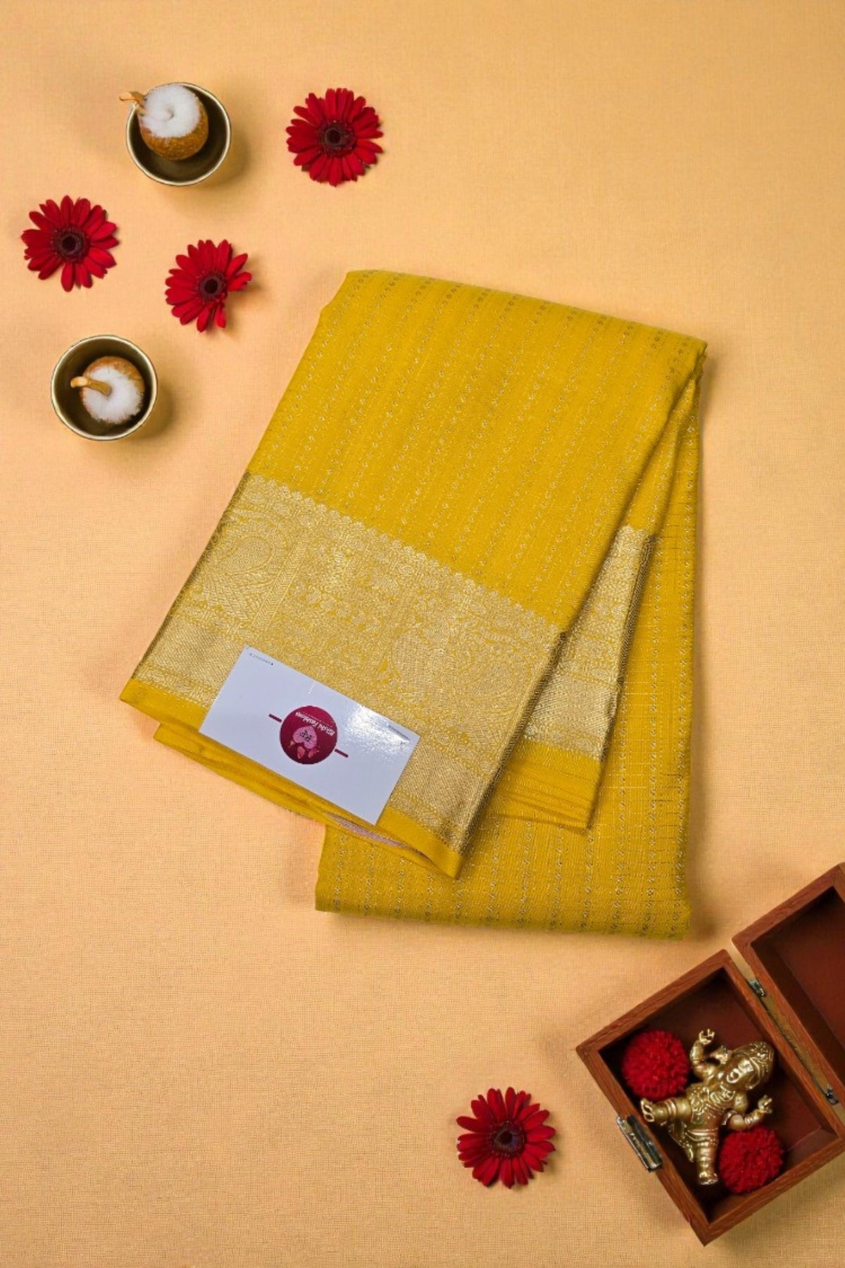 Yellow fabric with a gold border on a beige background with decorative elements.