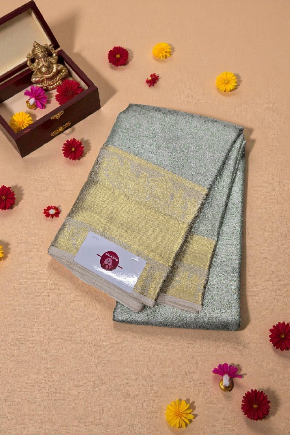 Gray and yellow saree with a wooden box and decorative items on a beige background