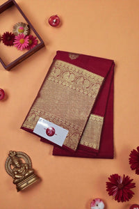 Maroon saree with gold embroidery on an orange background with decorative items.