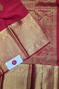 Red and gold saree with intricate patterns and a visible brand label.