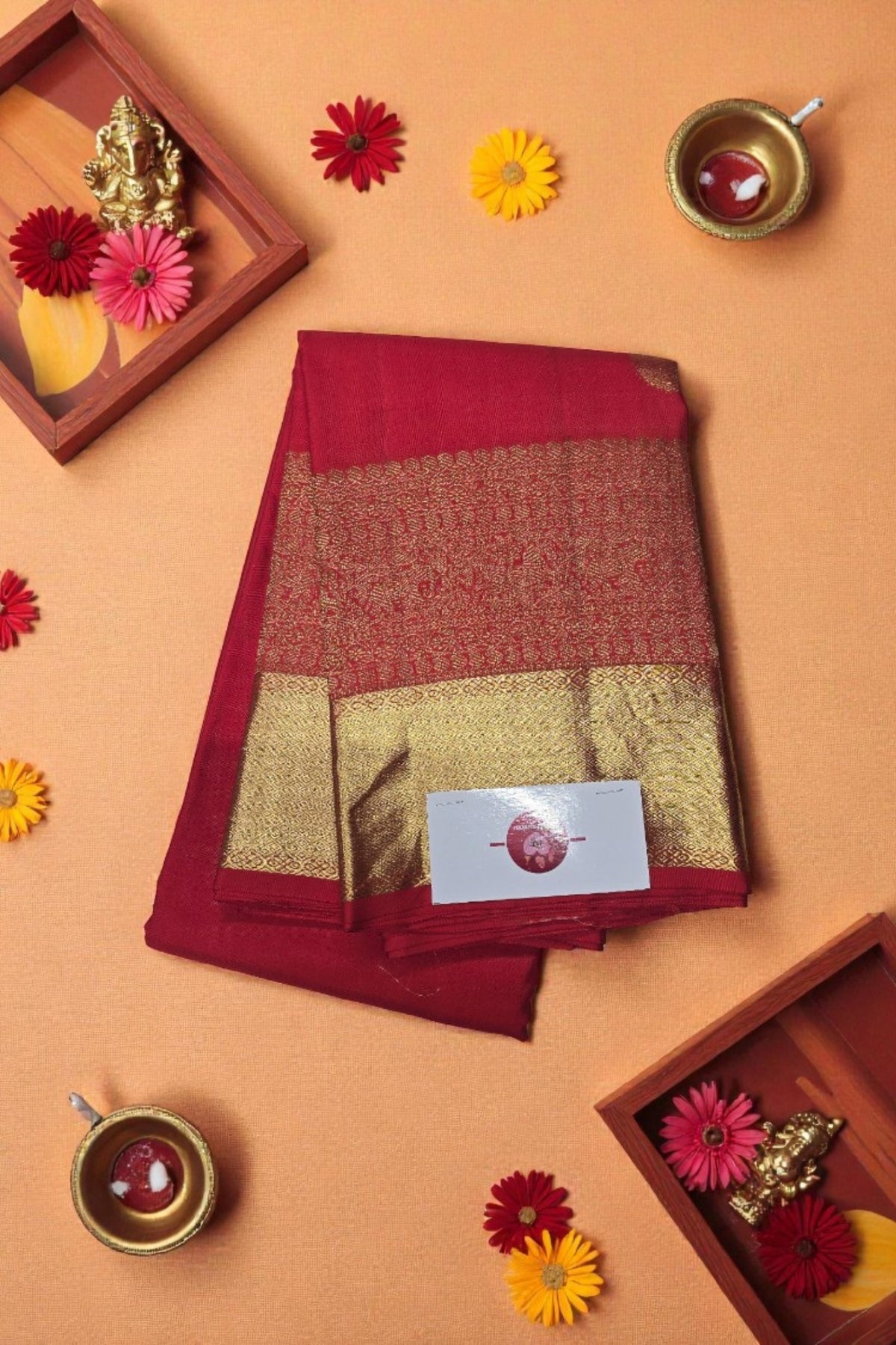Red and gold saree with decorative elements on a peach background
