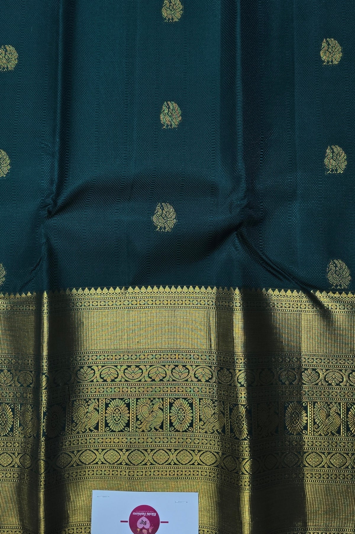 Dark green fabric with gold patterns and a visible brand label.