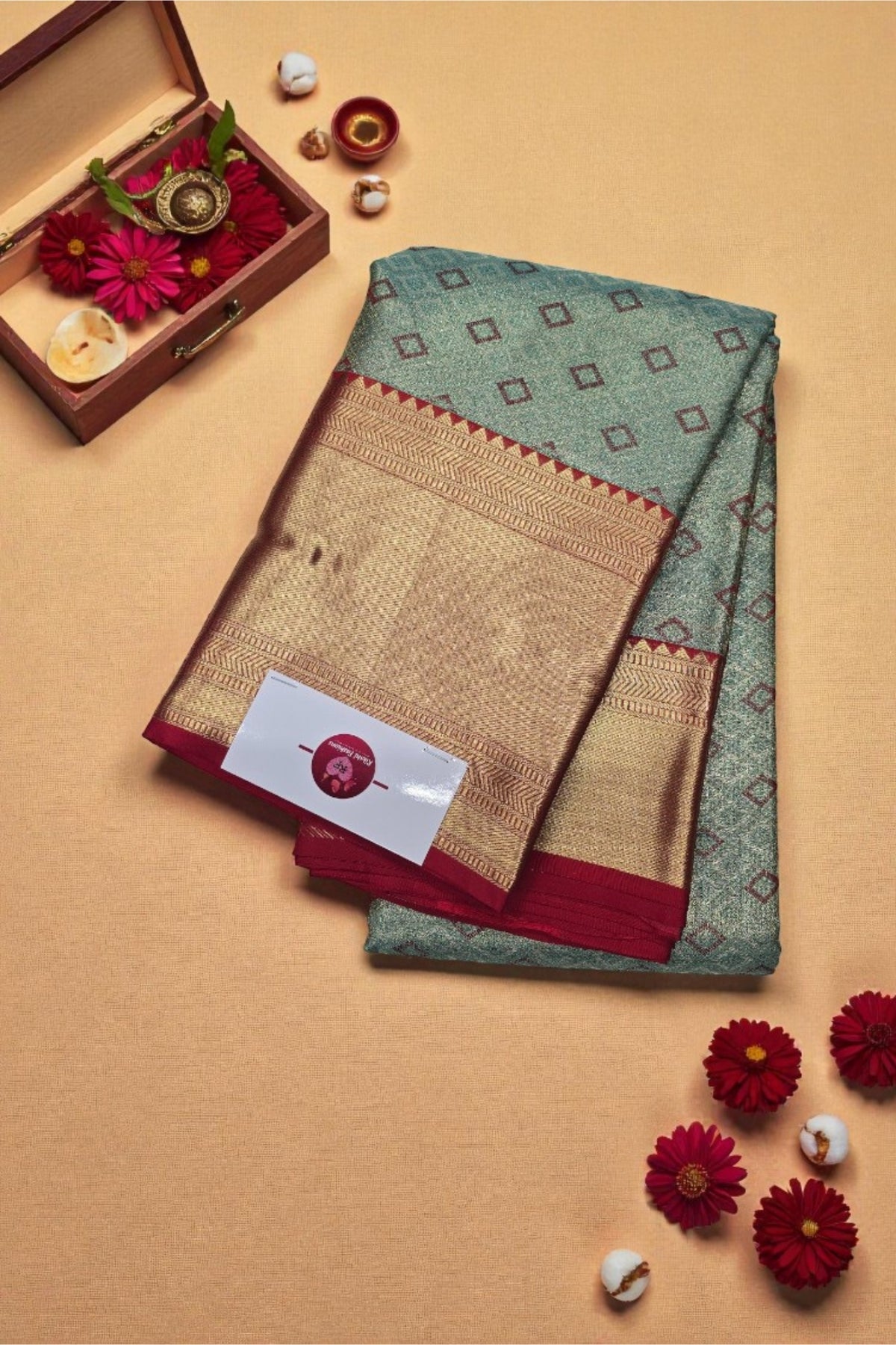 Traditional saree with a decorative box and flowers on a beige background